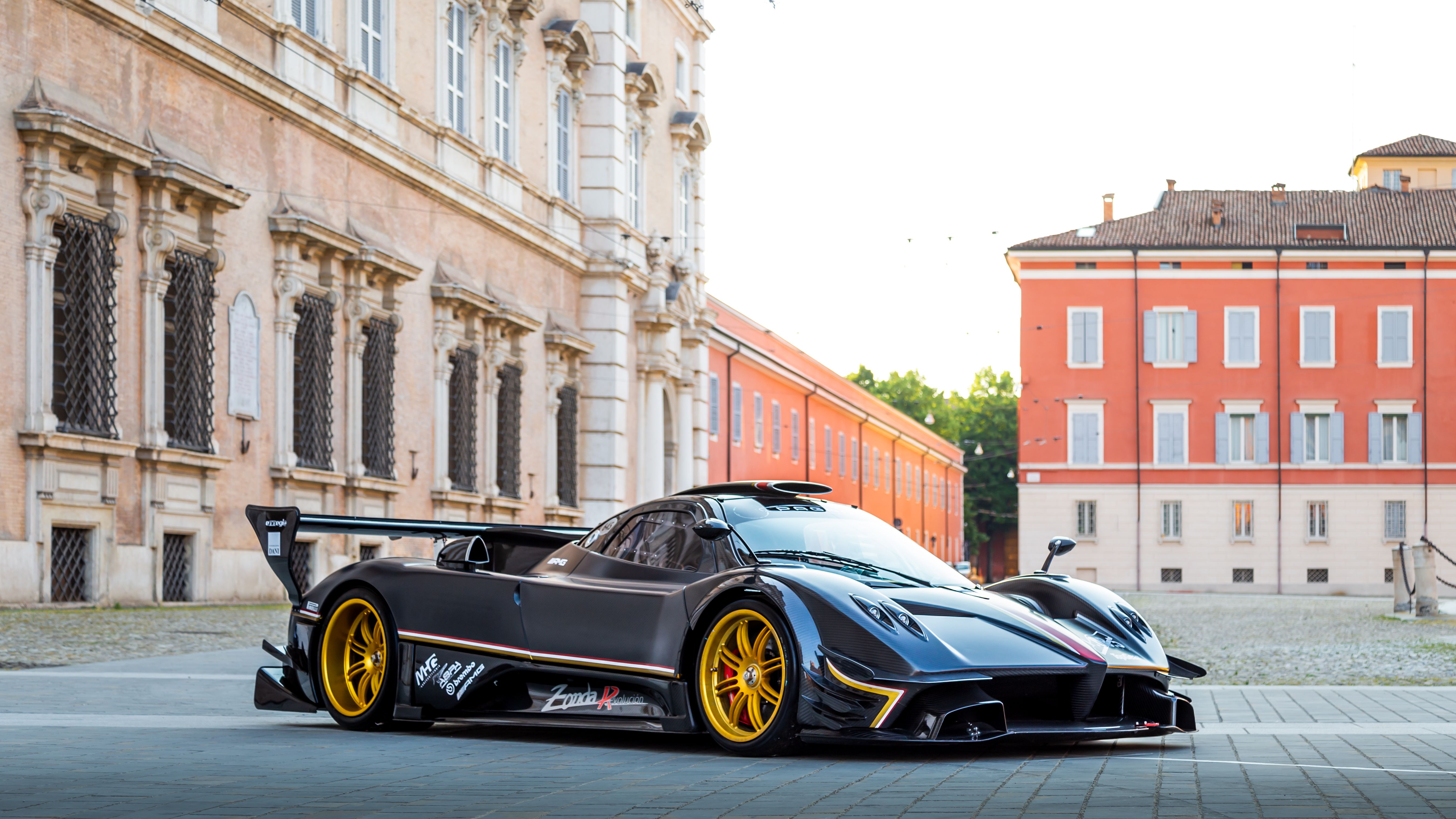 Black carbon Pagani Zonda Revolución with gold wheels parked in a Modena piazza
